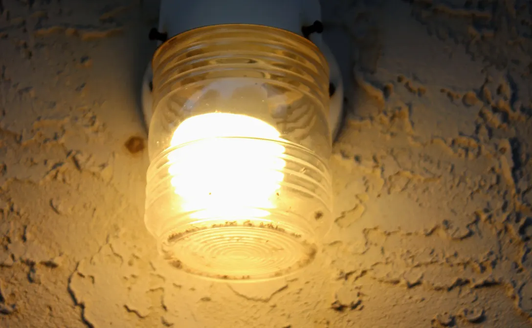 A porch light glowing warmly against a wall at night